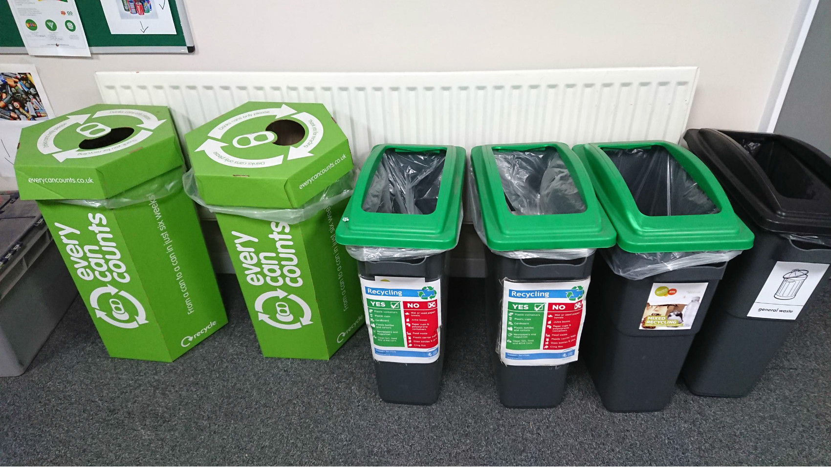 A row of different recycling containers, including some for cans and batteries, in an office at Canterbury Police Station.